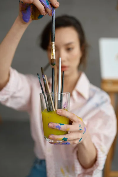 女性アーティスト水のガラスに絵筆機器を洗浄します ドローイングの供給を保持する画家の手に選択的な焦点 時間と芸術の創造性の概念 — ストック写真