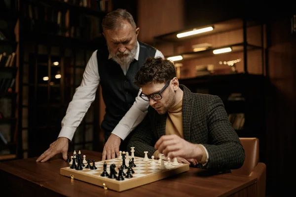 ゲームのルールを説明するチェスをする若い男を教える上級男性 教育レジャー国内活動 — ストック写真