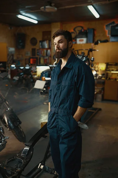 摩托车车库的维修和保养概念 穿着工作服站在车间背景上的英俊而严肃的修理工的画像 — 图库照片