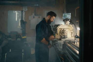 Görevli yedek parçaları yerleştirmek için torna yapmaya çalışıyor. Atölye konseptinde onarım çalışması