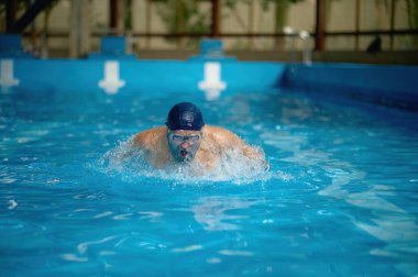 Son sınıf öğrencisi havuzda hızlı yüzüyor serbest stil eğitimi alıyor. Erkek emekli sportif yaşam tarzının ve aktif emekliliğin tadını çıkarıyor