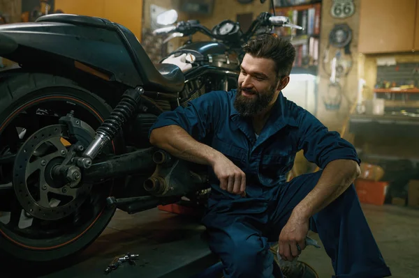 修理工場で良い仕事の後に修理バイクを見てうれしい笑顔のプロの整備士の気持ちを満足 — ストック写真