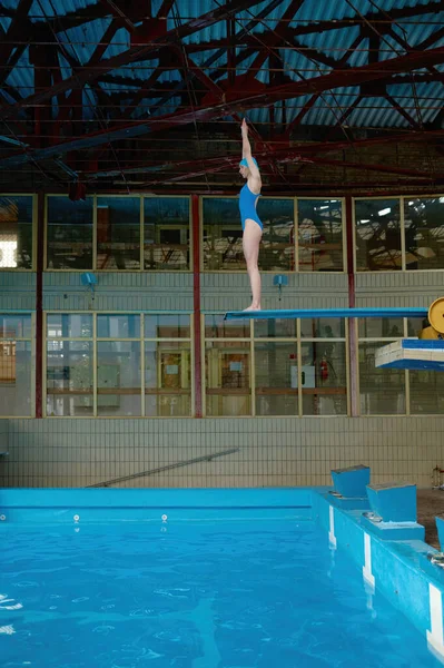 若いですスポーツ女性で水着立っています上のダイビングボードで公開スイミングプール準備ができてジャンプ — ストック写真