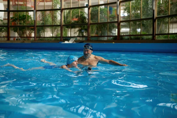屋内ジムプールで泳ぐ若い女性を教えるシニア男性インストラクター 女子学生の個人指導 — ストック写真
