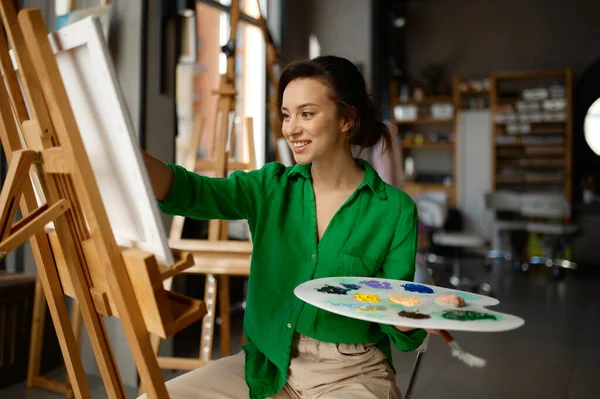 美術授業中のワークショップでキャンバスに幸せな若い女性の絵ブラシの肖像画 創作レジャー活動のコンセプト — ストック写真