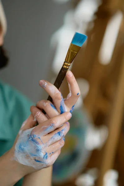 塗装ブラシを保持汚れた芸術家の手に焦点を当てたクローズアップショット プロのアートスタジオワークで絵を作成するための芸術楽器 — ストック写真