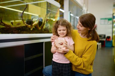 Mutlu anne ve küçük kızın portresi evcil hayvan dükkanından balık aldı.