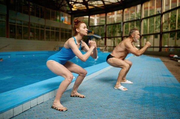 若い女性フィットネスインストラクター健康と柔軟性のためのストレッチ演習を行うスイミングプールで大人の男を訓練 — ストック写真