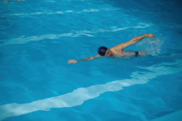 屋内スイミングプールで高速レースを楽しむ運動を行うプロのシニア男性水泳選手 高齢者のためのカーディオスポーツ活動コンセプト — ストック写真