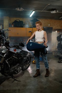 Garaj atölyesinde bisikletle tamirat sırasında yakıt deposunu tamir eden kadın üstat.