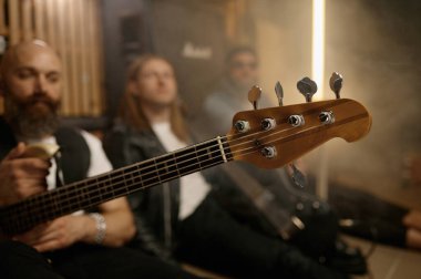 Moda kıyafetleri içinde funky rock grubu müzisyeni prova tekrarından sonra dinleniyor. Davulcu, solo ve bas gitarist stüdyoda yerde oturuyor.