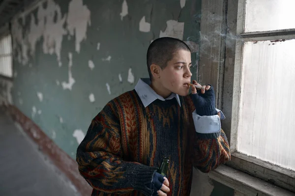 在窗前遭受尼古丁和酒精成瘾折磨的朋克女乞丐 — 图库照片