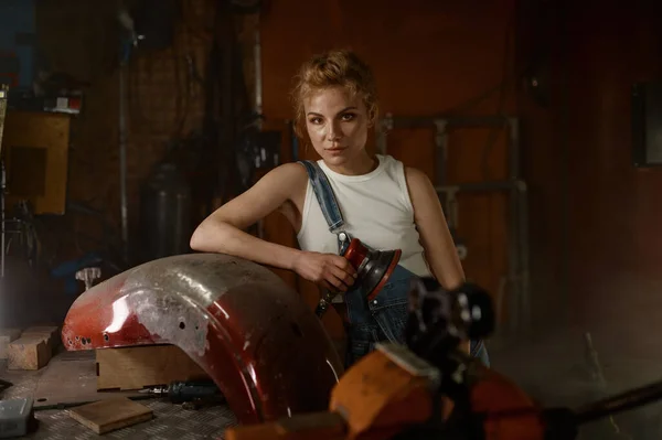 有魅力的女人在摩托车修车厂用磨床修理一些金属自行车零件 — 图库照片