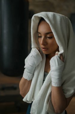 Kickboks bandajlı genç kadın boksörün yakın plan portresi. Havluya sarılı ve antrenmandan sonra yorgun hissediyor. Spor, spor, yaşam tarzı ve insanlar konsepti