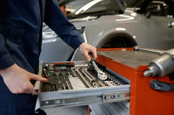 車の修理のためのプロのガレージサービスで作業しながら 男性の自動車技術者の手でツールキットボックスからレンチ楽器を取ります — ストック写真