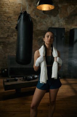 Omuzlarında havluyla kameraya bakan tatmin olmuş kadın boksör. Spor, hobi ve kişisel başarı konsepti