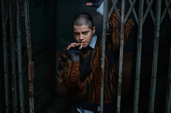忧心忡忡的妇女乞丐 嘴里叼着香烟 被关在牢里 看着旁边 感到无助和绝望 — 图库照片
