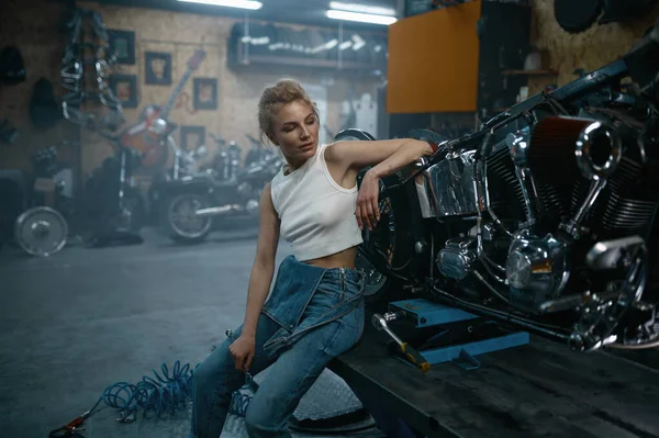 オートバイのガレージでカメラのためにポーズ魅力的な女性の整備士 本物のワークショップでプロの修理の女性 — ストック写真