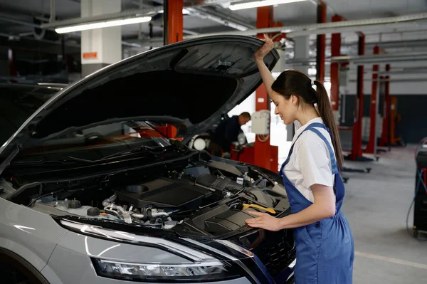 Junge Automechanikerin Schaut Unter Die Motorhaube Während Sie Der Werkstatt — Stockfoto