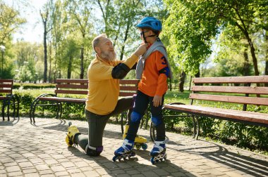 Mutlu aile hafta sonu şehir parkında patene hazırlanıyor. Baba oğlunun kafasına koruyucu kask takıyor.