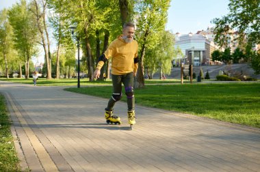 Şehir parkında paten kayarken mutlu bir olgun adam. Son sınıf öğrencisi hafta sonları spor yaparken eğleniyor ve eğleniyor.