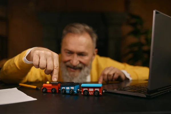 Yerinde Masada Dizüstü Bilgisayarla Oyuncak Trenle Oynayan Yaşlı Adamın Seçici — Stok fotoğraf