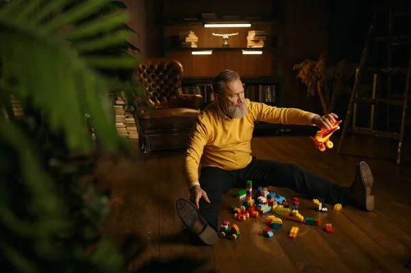 Šťastný Nadšený Starý Důchodce Hraje Hračky Zatímco Sedí Domácí Podlaze — Stock fotografie