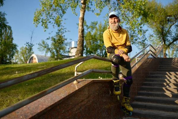 坐在城市公园的楼梯栏杆上休息 脸上挂着滑冰鞋的老人开心地微笑着 退休时的实际工作时间 — 图库照片