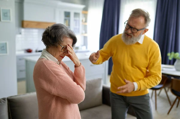 Angry elderly husband shouting on elderly upset wife. Mature spouses problems in marriage concept