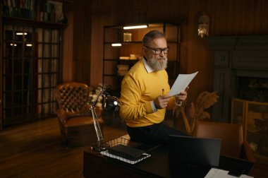 Akşamları evde çalışırken kağıt okumakla meşgul yetişkin bir adam. Son sınıf öğrencisi, bilgisayar başında oturmuş mali gelirleri kontrol ediyor.