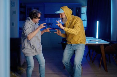 Ev mutfağında dans eden iki yaşlı insan birlikte iyi vakit geçiriyorlar. Modern elbiseli yaşlı bir çift emeklilikten hiç sıkılmıyor.