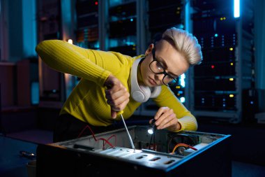 Modern ağ sunucu odasının kontrol odasında çalışan tornavida kullanarak bilgisayar sistemi tamir eden genç bir bilişim kadını.