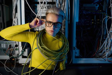 Sunucu odasında ağ kablolarına sarılı yorgun kadın bilişim mühendisinin portresi