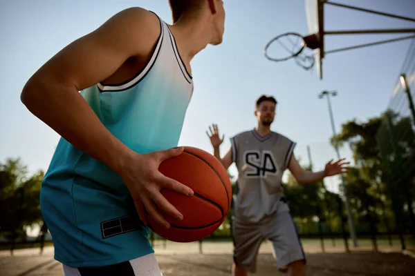 Closeup teenager boy preparing to throw ball into basket hoop. Happy dad and son playing basketball on outdoor street court