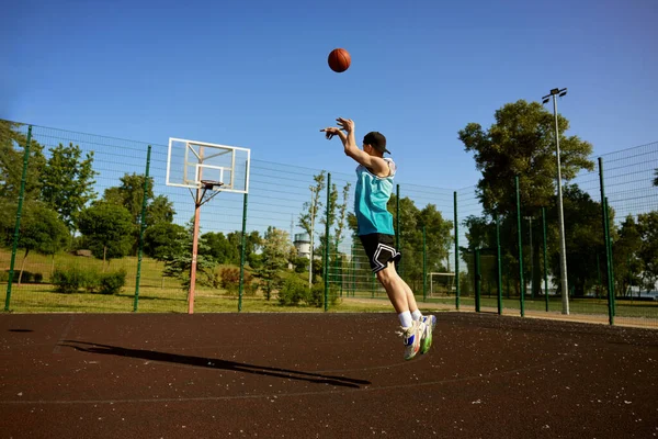 活跃的少年在街头露天场地打篮球 小男孩用球瞄准篮筐跳跃 — 图库照片