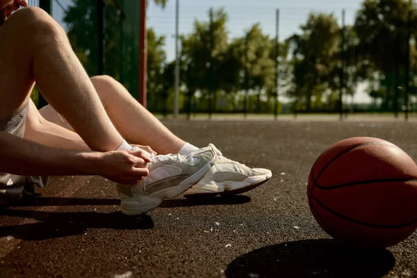 运动员在篮球场上的运动鞋上绑鞋带的剪影 赛前准备工作 — 图库照片