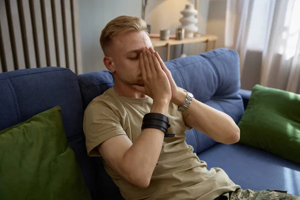 stock image Depressed soldier suffering from military PTSD sharing his concerns covering face with hands while sitting on sofa at therapy session. Veteran rehabilitation concept