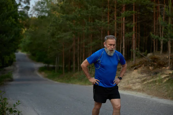 Tired retired sportsman breathing hard after jogging exercise. Sport training outdoors and everyday running activity for healthcare on retirement motivation