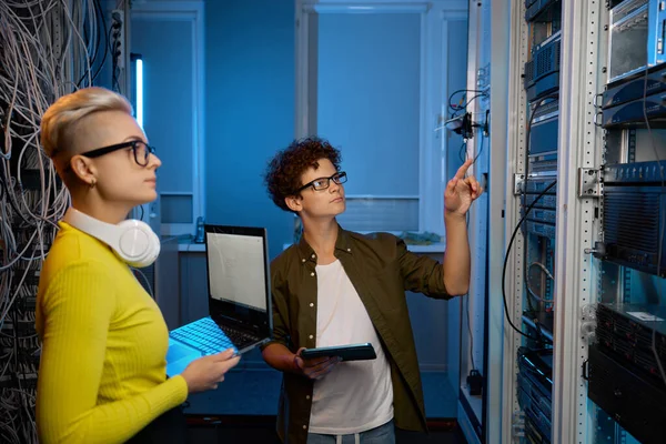 スーパーコンピュータが付いている現代ビジネス データ センターの暗いサーバー部屋のネットワーク ハードウェアと協力する深刻な技術者 — ストック写真