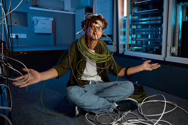 混乱したItネットワーキングエンジニアは イーサネットケーブルや光学ワイヤーに不信感を持って見ています 職場での困難 — ストック写真