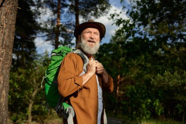 Mutlu gülümseyen olgun erkek turistin portresi direkleri ile bütün günü dışarıda yürüyüş yaparak geçiriyor.