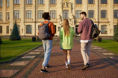 Sırt çantalı bir grup öğrenci sabah sınıfına giderken kampüs yolunda birlikte yürüyorlar. Eğitim ve burs fırsatı