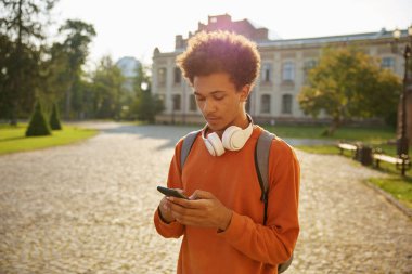 Dışarıda cep telefonu kullanan genç bir öğrenci. Lisede, üniversitede ya da üniversitede ara