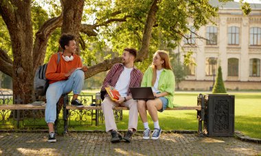 Kendine güvenen üniversite öğrencileri kampüs parkında dinlenirken sohbet ediyorlar. Uluslararası milenyum insan grubunun güzel sohbeti.
