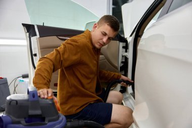 Adam elektrikli süpürge makinesiyle arabanın içini kuru temizlemeye vermiş. Nakliye bakım ve hijyen hizmetleri