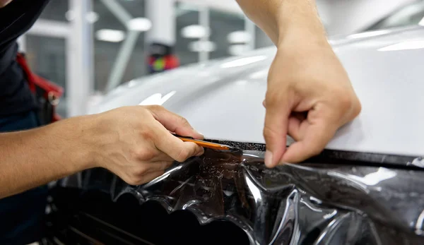 汽车详细专家把乙烯箔或薄膜放在汽车罩的特写 汽车修理厂服务 — 图库照片