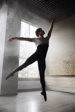 Genç stil sahibi modern erkek balerin hareket halinde. Profesyonel koreograf dumanlı stüdyo arka planında performans sergiliyor
