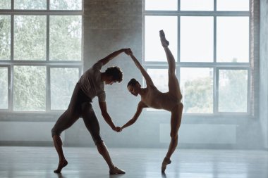 Erkek ve kadın dansçıların silueti stüdyo arka planına karşı birlikte gösteri yapıyor. Çağdaş koreografi performansı