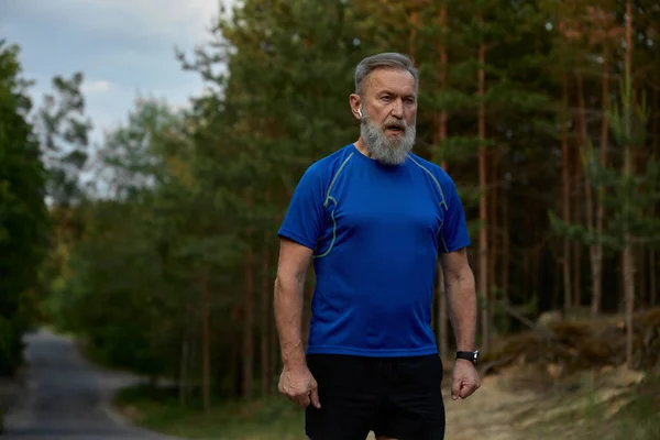Tired retired sportsman breathing hard after jogging exercise. Sport training outdoors and everyday running activity for healthcare on retirement motivation