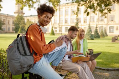 Üniversite öğrencileri kampüste ödev ya da yaratıcı proje üzerinde çalışıyor. Neşeli sınıf arkadaşları eğlenceli eğitim sürecinin tadını çıkarıyorlar.